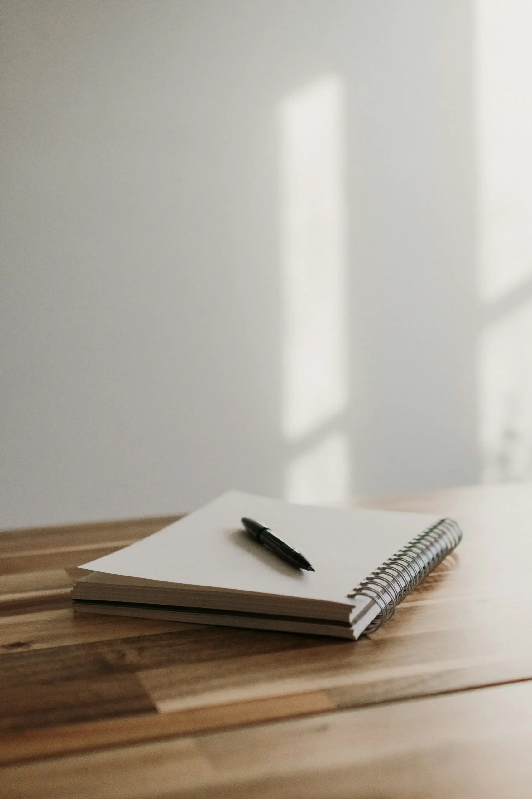 Blank white notebook with a pen on a minimal desk