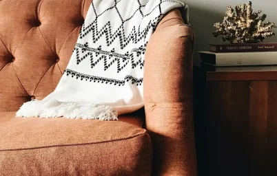 Cozy armchair with a patterned blanket draped over it.