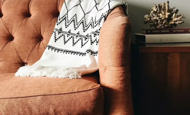 Cozy armchair with a patterned blanket draped over it.