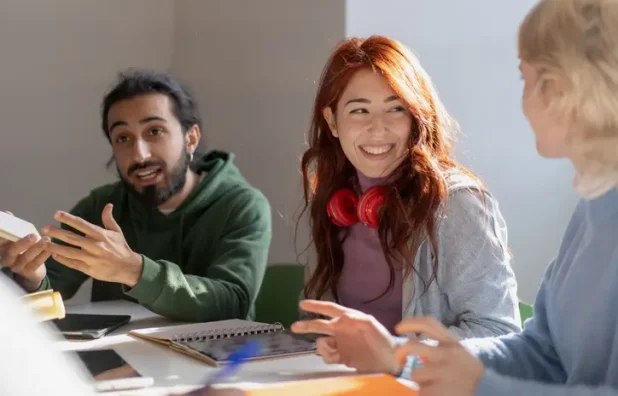 Small group of young adults smiling and studying together.
