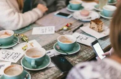 People having coffee and looking at papers on a table.