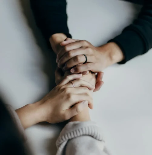 Two people holding hands in a supportive gesture on a table.